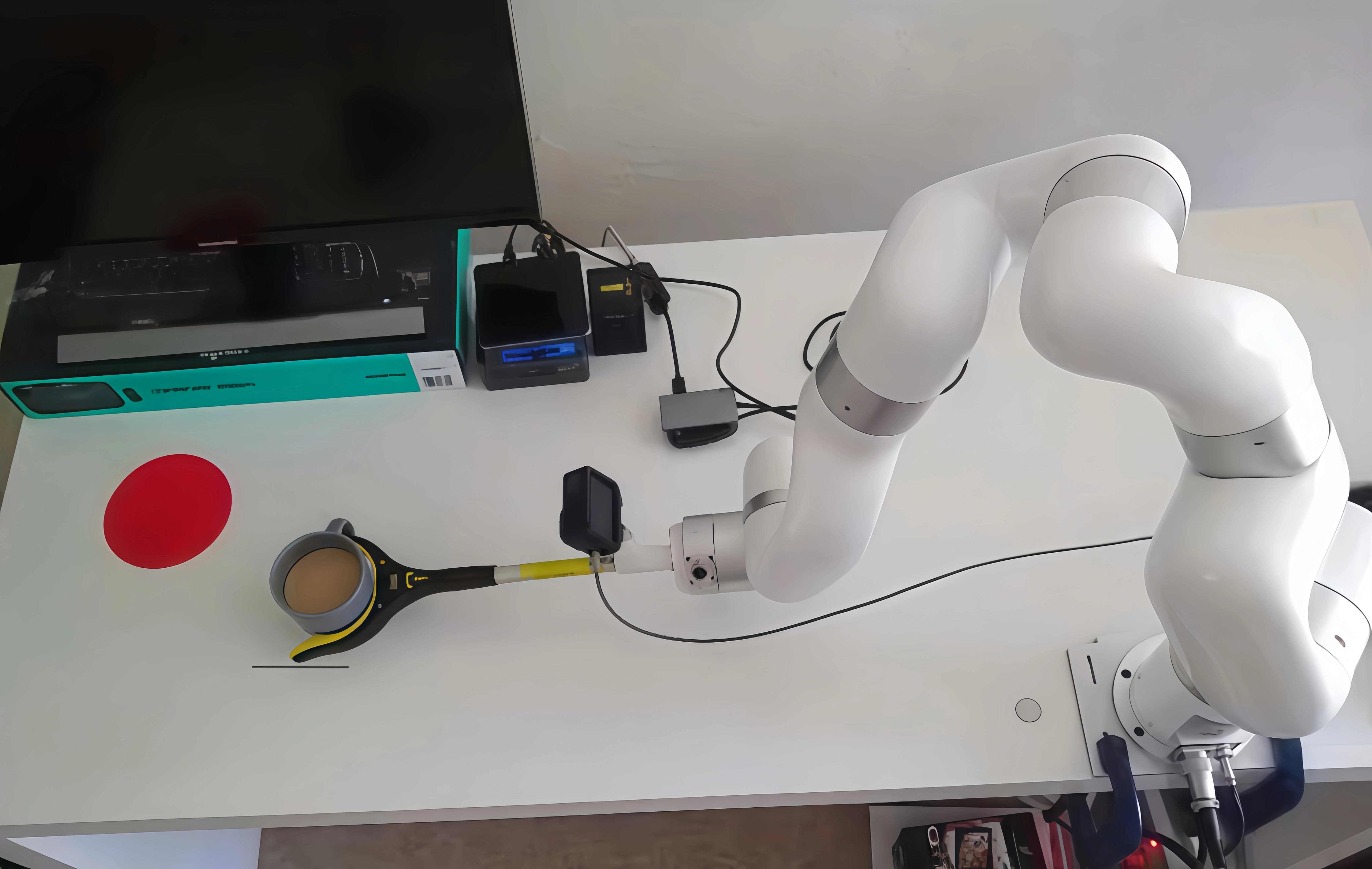 xArm 7 with a camera-mounted reacher-grabber moves a cup to the red target area during a tabletop manipulation task