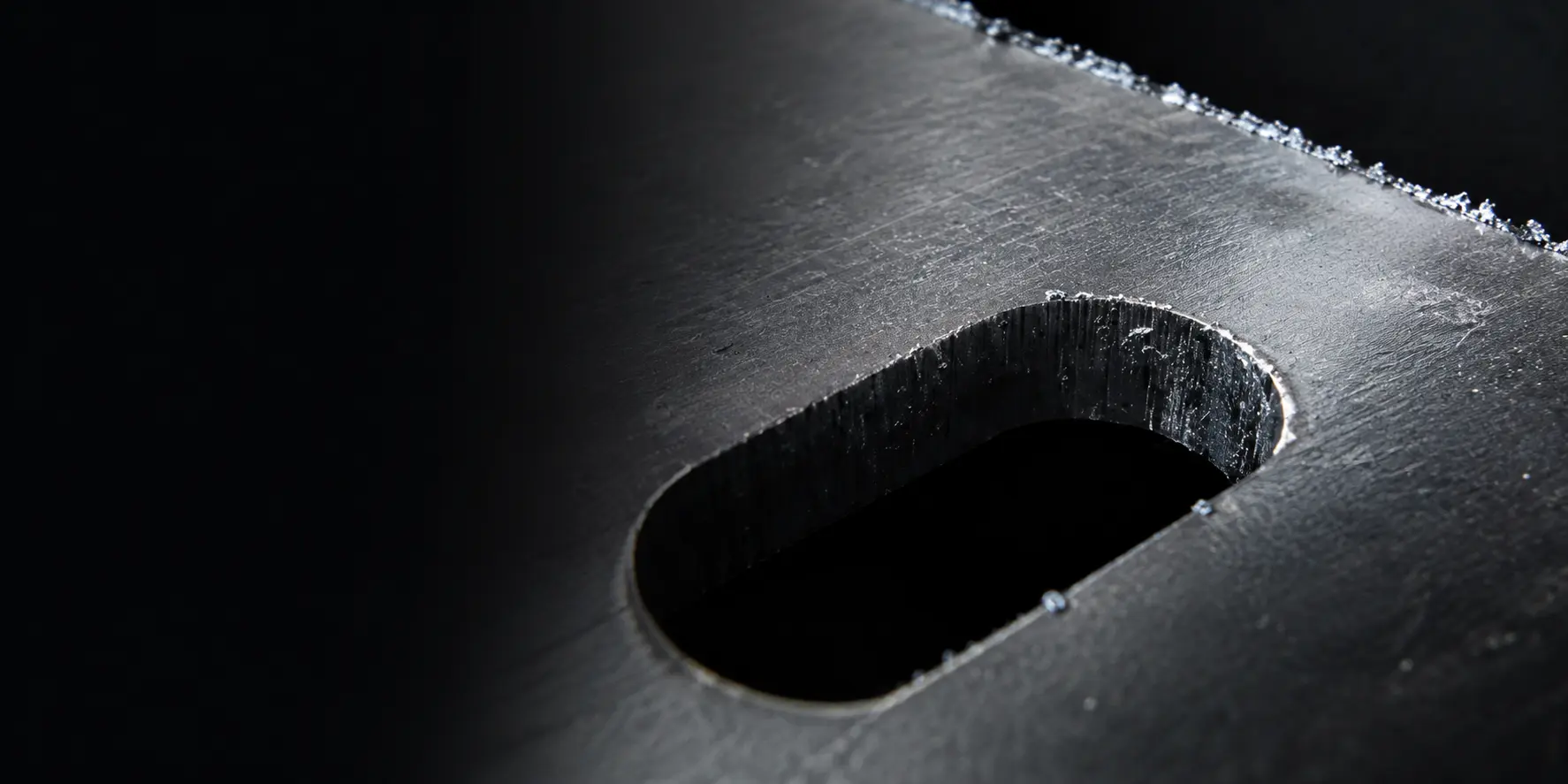 Close-up of a machined slot in a metal part with burrs still attached along the edges