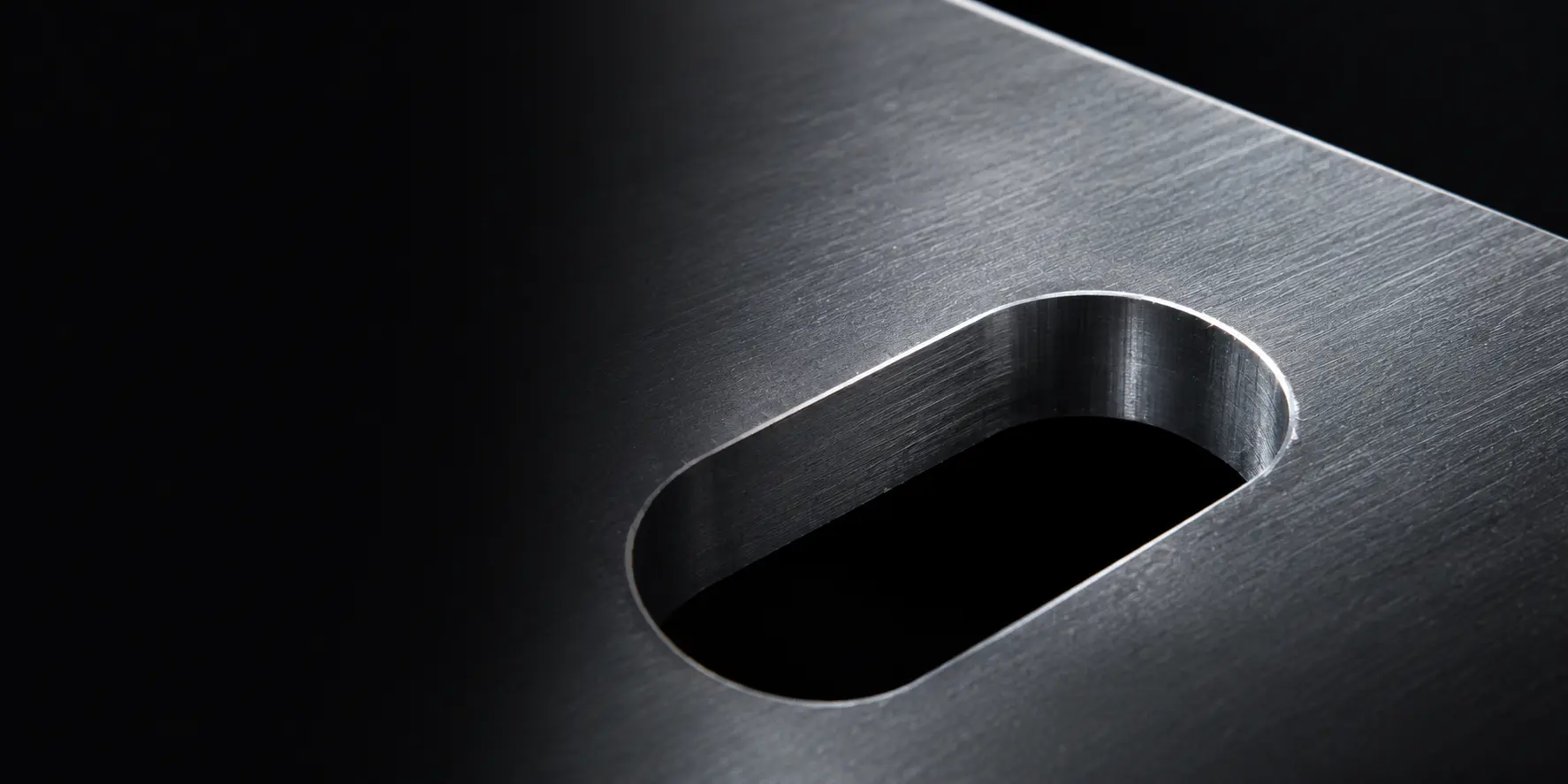 Close-up of a machined slot in a brushed metal part with deburred edges