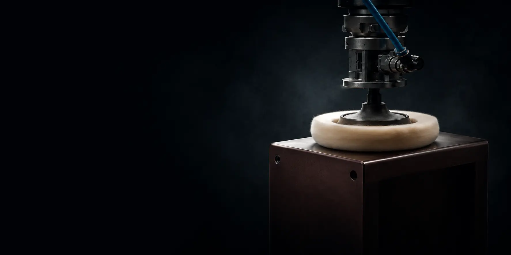 Buffing wheel on a robot-mounted spindle polishing the top face of a wooden enclosure