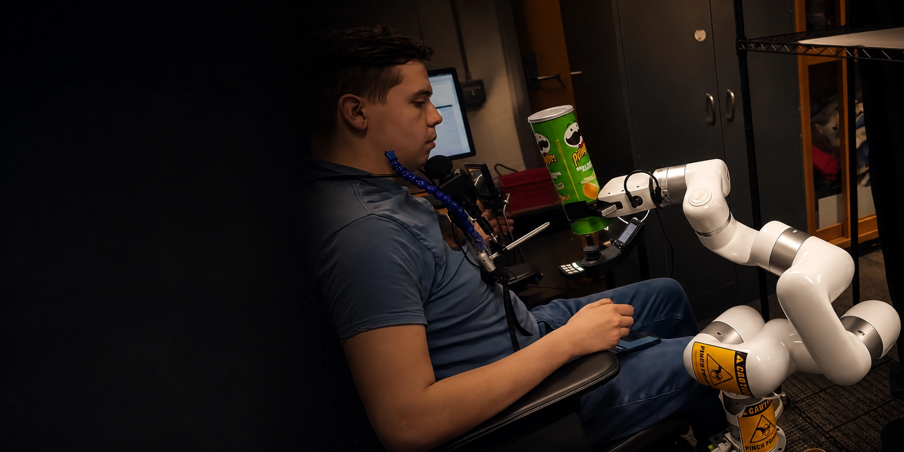 Wheelchair user with a mouth-operated interface controlling a UFACTORY xArm 6 to hold a snack container within reach