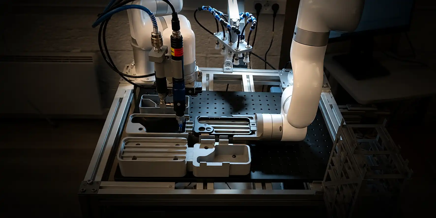 UFACTORY cobot dispensing cell with a vacuum gripper array and phone enclosure fixtures on a workbench