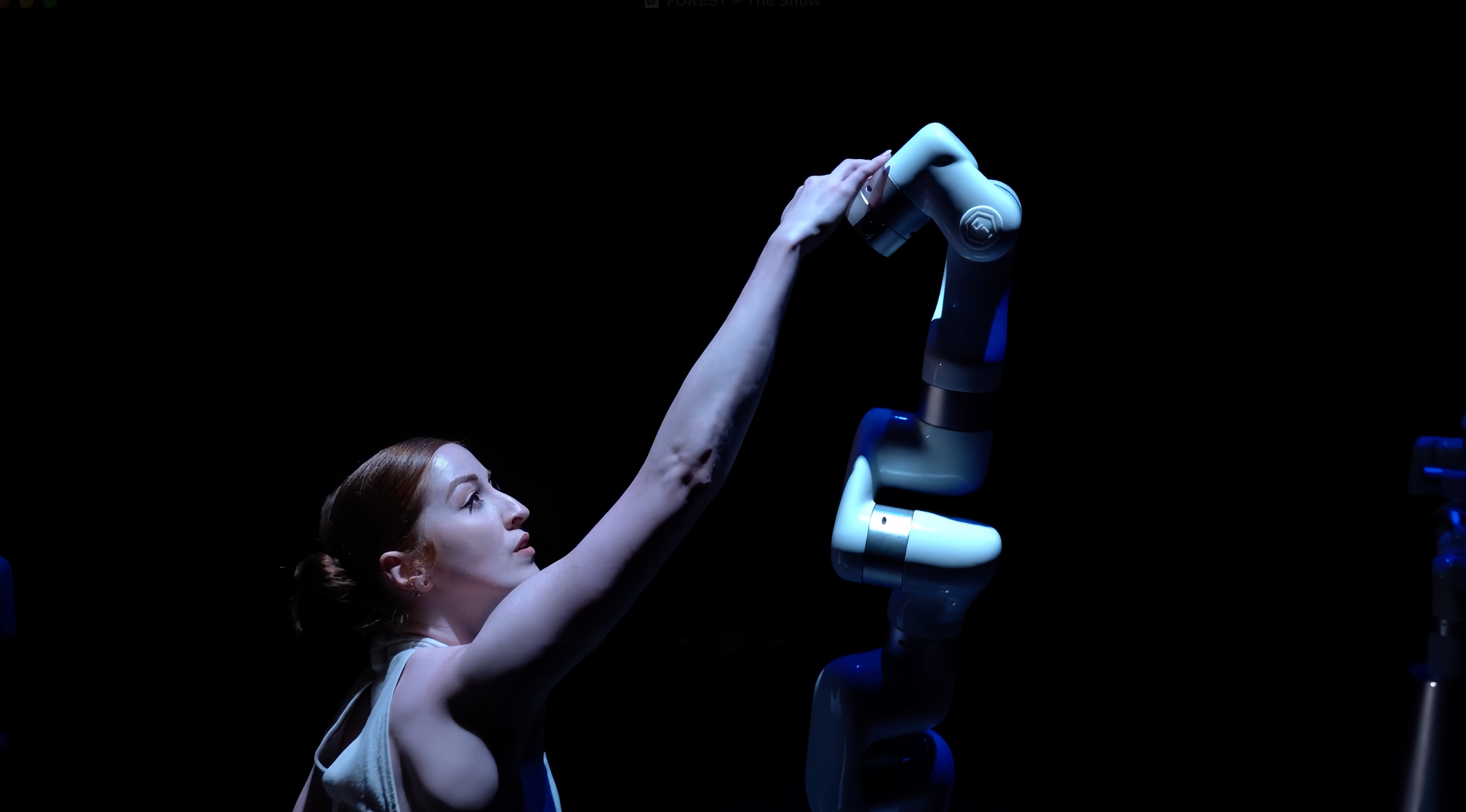 Dancer reaches toward an xArm cobot during a human-robot dance performance