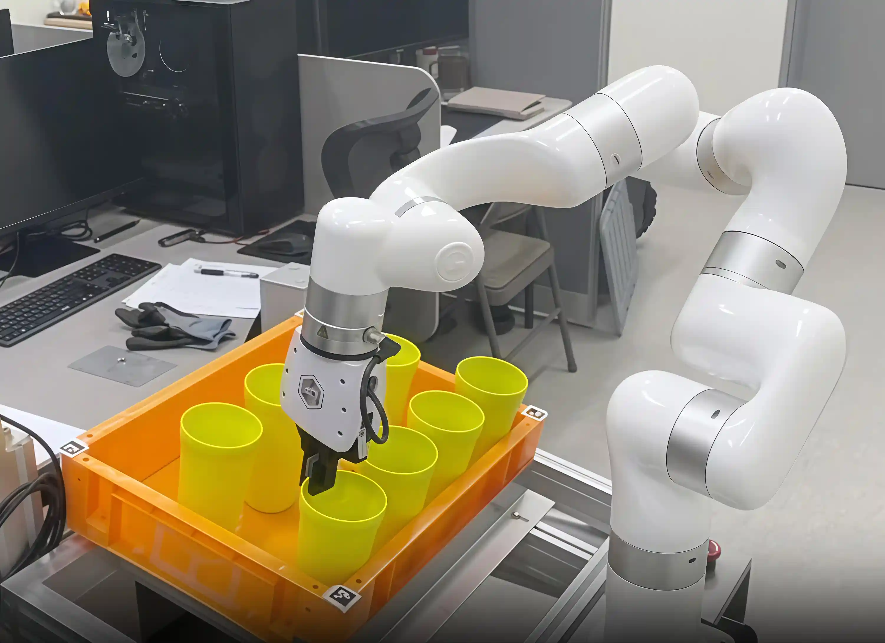 xArm positions its gripper over yellow containers in an orange bin during a robotic bin-picking test