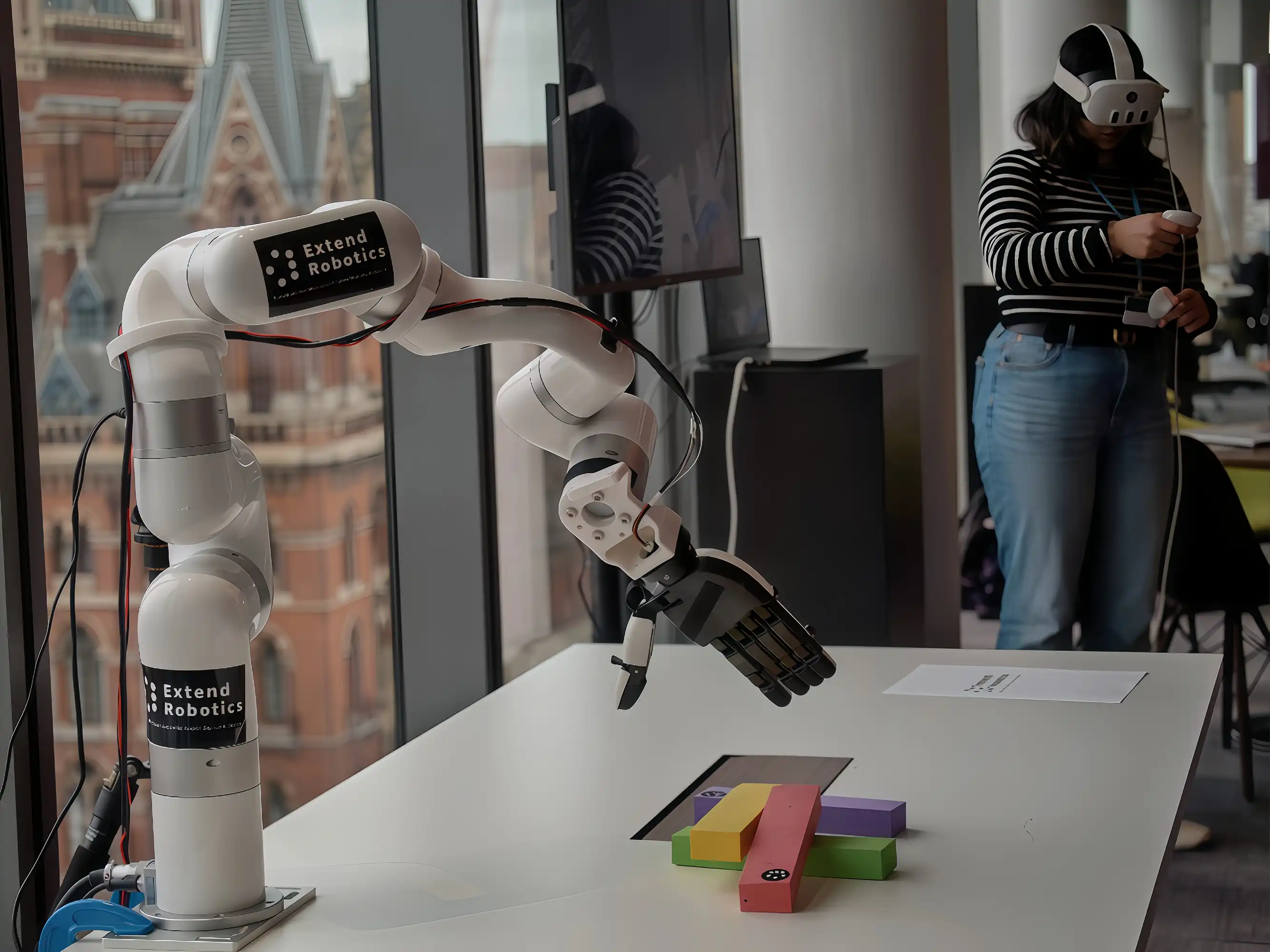 Operator wearing a VR headset remotely controls a UFACTORY xArm with a dexterous hand over colored blocks